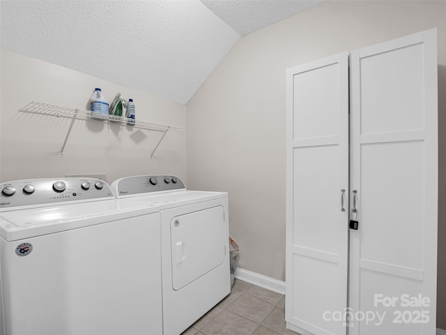 laundry room featuring washing machine and clothes dryer, light tile patterned floors, and a textured ceiling