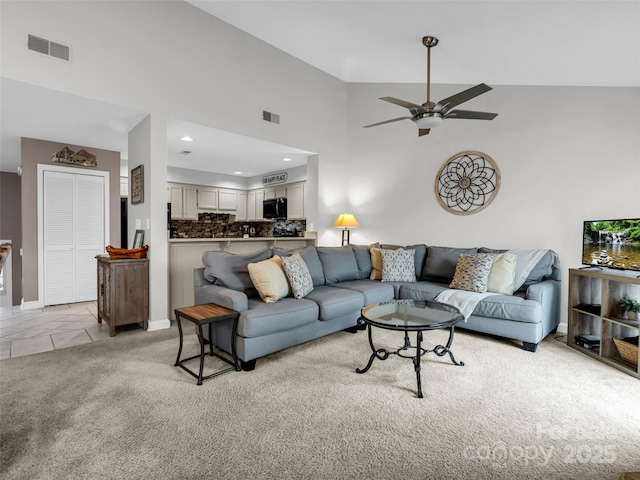 living room with ceiling fan, light colored carpet, and high vaulted ceiling