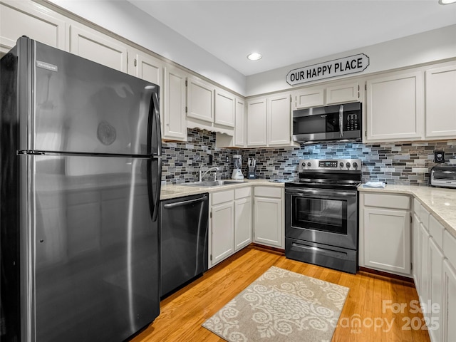 kitchen with white cabinets, sink, light wood-type flooring, and stainless steel appliances