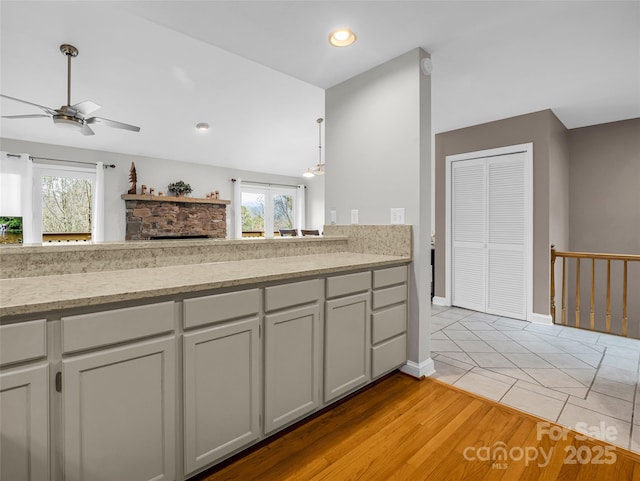 kitchen with a fireplace, light hardwood / wood-style floors, a wealth of natural light, and ceiling fan