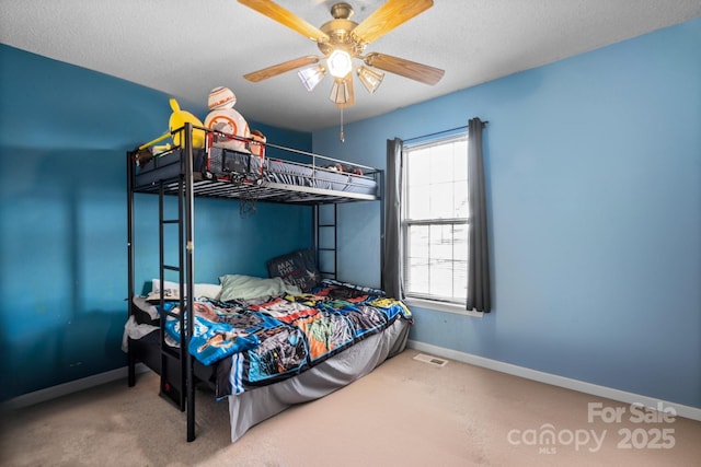 bedroom featuring ceiling fan, carpet floors, and a textured ceiling