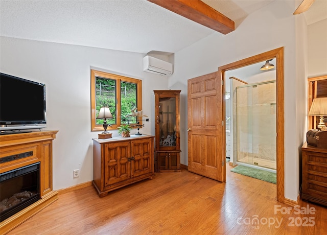 41 Cottontail Ln, Canton, NC 28716 - entryway with a wall unit AC, light wood-style floors, beamed ceiling, a glass covered fireplace, and baseboards