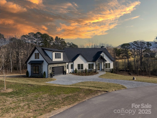 view of front facade featuring a lawn, a mountain view, and a garage