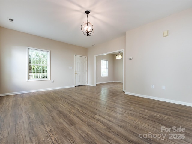 unfurnished room with a chandelier, dark hardwood / wood-style flooring, and plenty of natural light