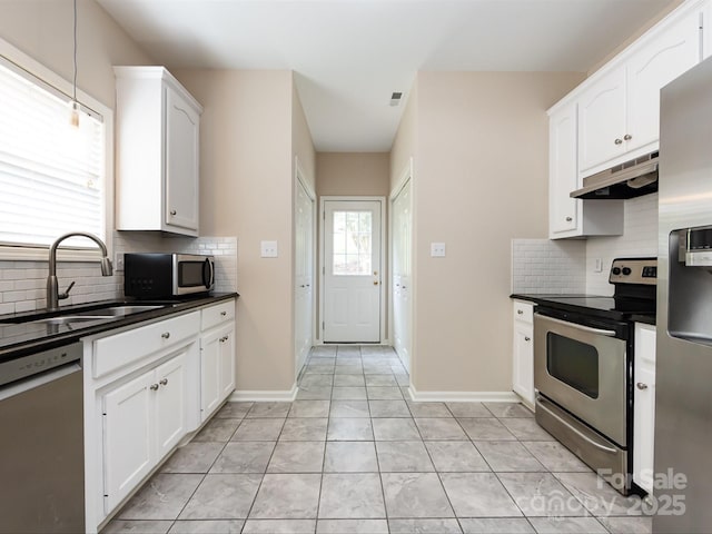 kitchen with sink, light tile patterned floors, appliances with stainless steel finishes, tasteful backsplash, and white cabinetry