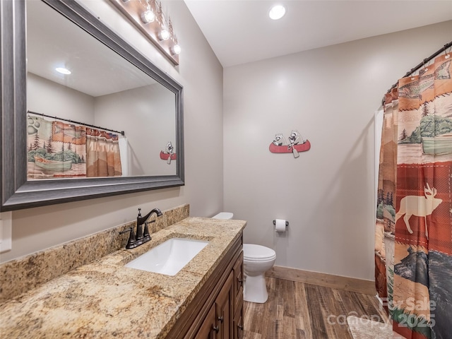 bathroom with a shower with shower curtain, vanity, wood-type flooring, and toilet