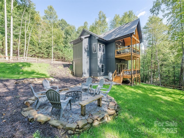 rear view of house with a fire pit, a deck, and a lawn