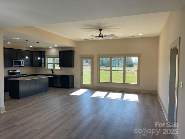 kitchen with dark hardwood / wood-style flooring, stainless steel appliances, ceiling fan, pendant lighting, and a kitchen island