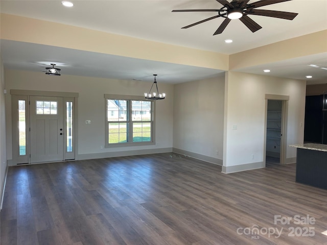 interior space with ceiling fan with notable chandelier and dark wood-type flooring