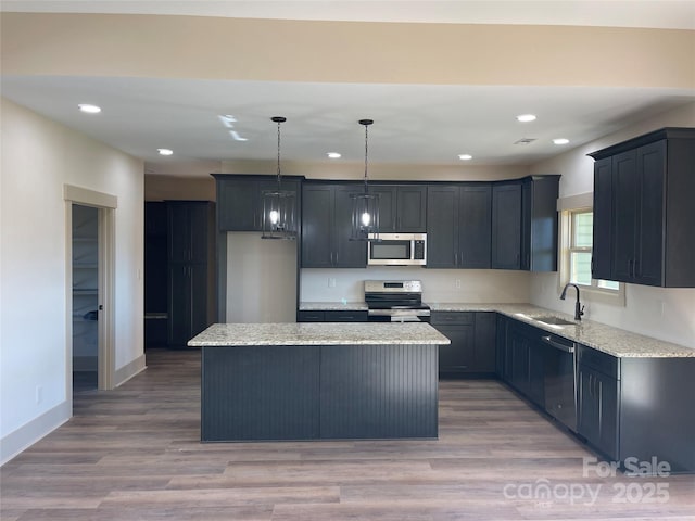 kitchen featuring pendant lighting, sink, hardwood / wood-style flooring, a kitchen island, and stainless steel appliances