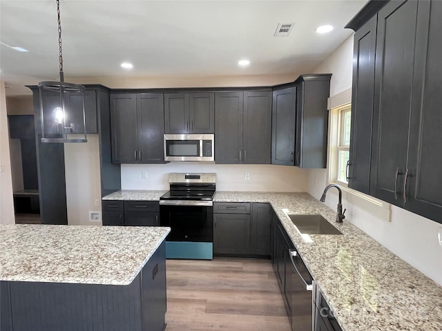 kitchen featuring pendant lighting, sink, light stone countertops, light hardwood / wood-style floors, and stainless steel appliances