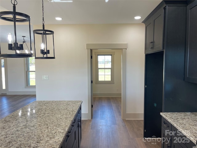 kitchen featuring decorative light fixtures, dark hardwood / wood-style floors, light stone counters, and a chandelier