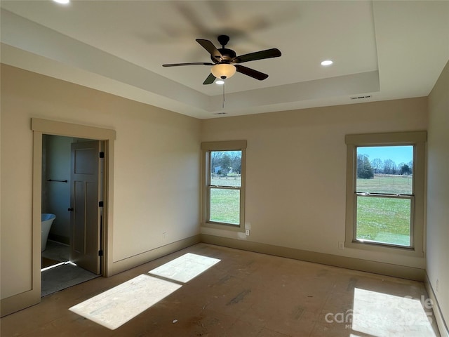 spare room featuring a tray ceiling, plenty of natural light, and ceiling fan