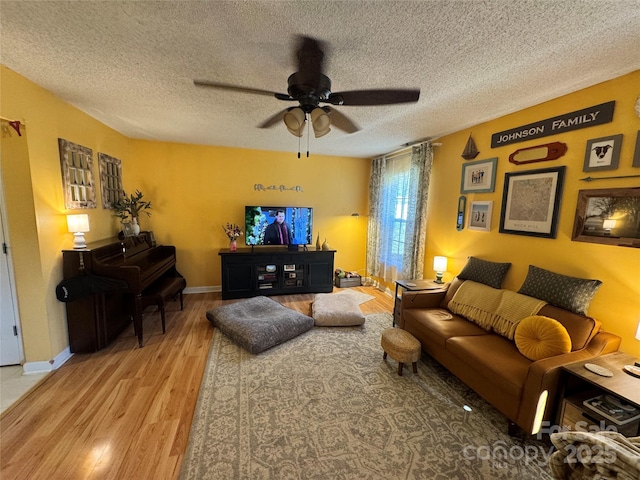 living room with ceiling fan, wood-type flooring, and a textured ceiling