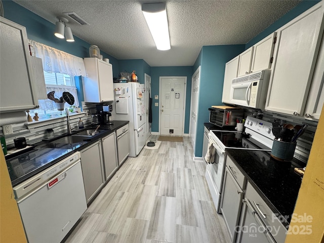 kitchen featuring backsplash, a textured ceiling, white appliances, sink, and white cabinetry