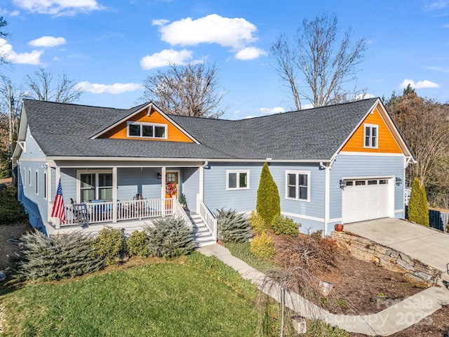 view of front of home featuring covered porch, a garage, and a front yard