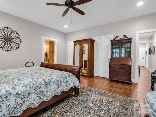 bedroom with ceiling fan, ensuite bathroom, and dark wood-type flooring