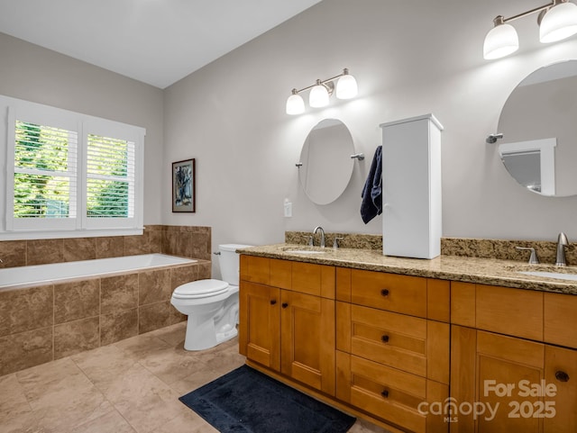 bathroom with tile patterned flooring, vanity, toilet, and tiled bath