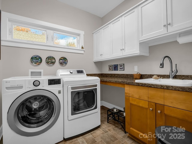 washroom with washing machine and clothes dryer, cabinets, and sink