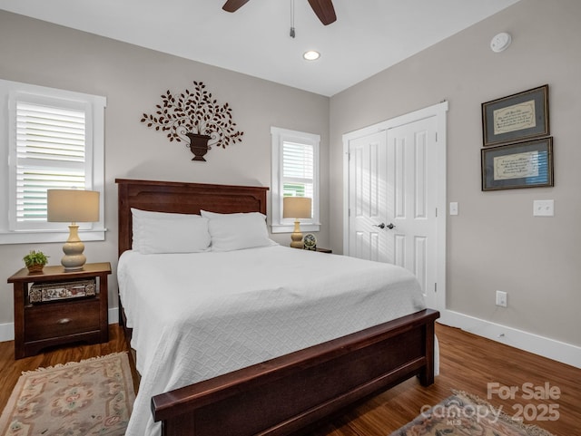 bedroom with ceiling fan, dark wood-type flooring, and a closet