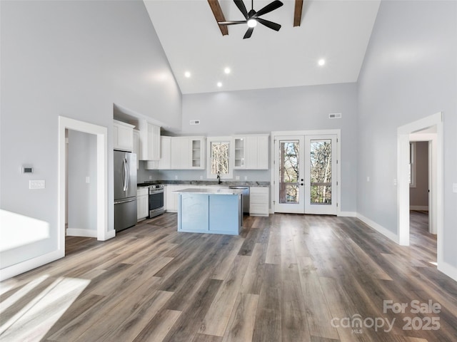 kitchen featuring a high ceiling, french doors, white cabinets, a kitchen island, and stainless steel appliances