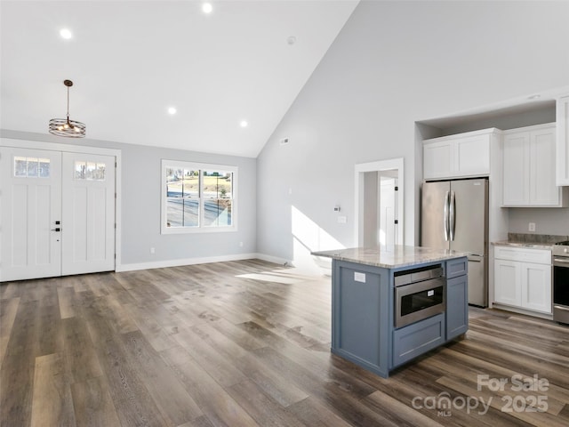 kitchen with white cabinetry, high vaulted ceiling, hanging light fixtures, and appliances with stainless steel finishes