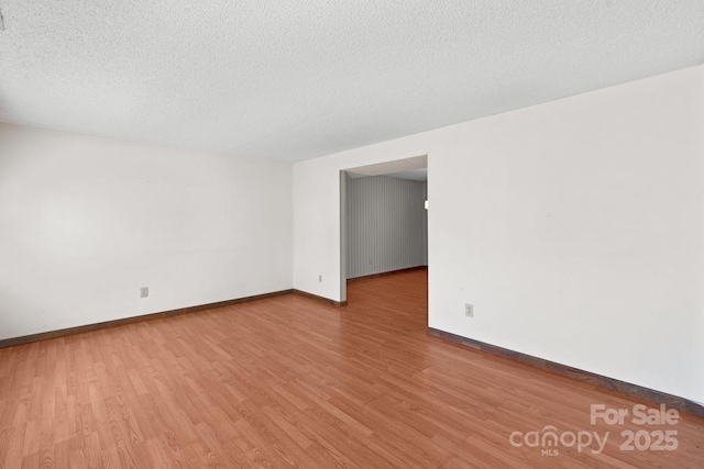 empty room with light hardwood / wood-style floors and a textured ceiling