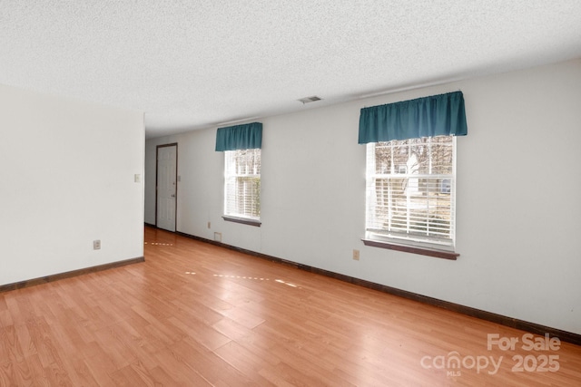 empty room featuring a textured ceiling and hardwood / wood-style floors