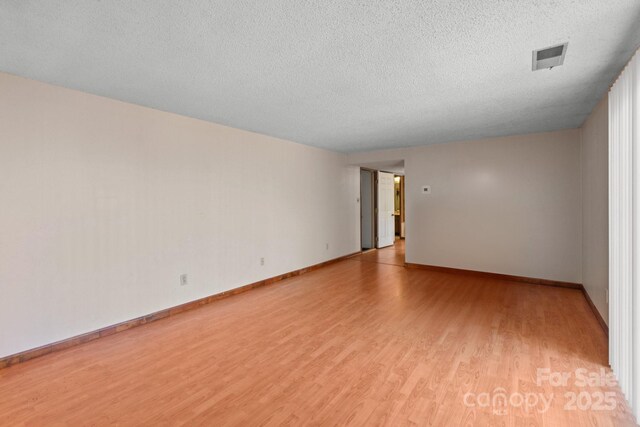 unfurnished room with a textured ceiling and light hardwood / wood-style flooring