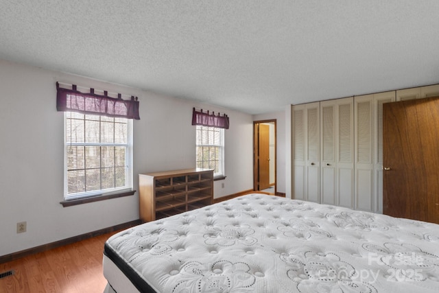 bedroom with a textured ceiling, a closet, and hardwood / wood-style flooring