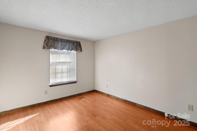 spare room with a textured ceiling and hardwood / wood-style floors