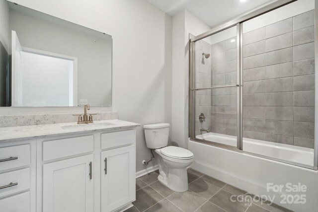 full bathroom featuring tile patterned flooring, bath / shower combo with glass door, vanity, and toilet