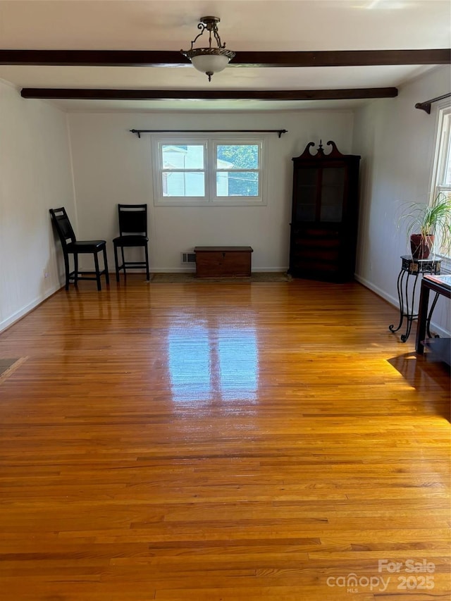 living room with a healthy amount of sunlight, light wood-type flooring, and beam ceiling