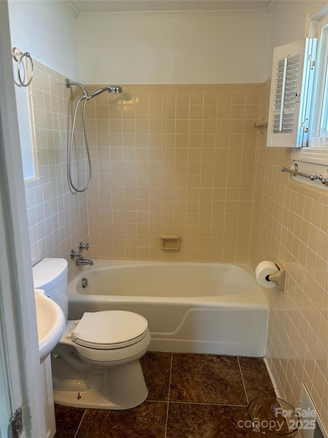 bathroom with tile patterned floors, toilet, tiled shower / bath, and tile walls