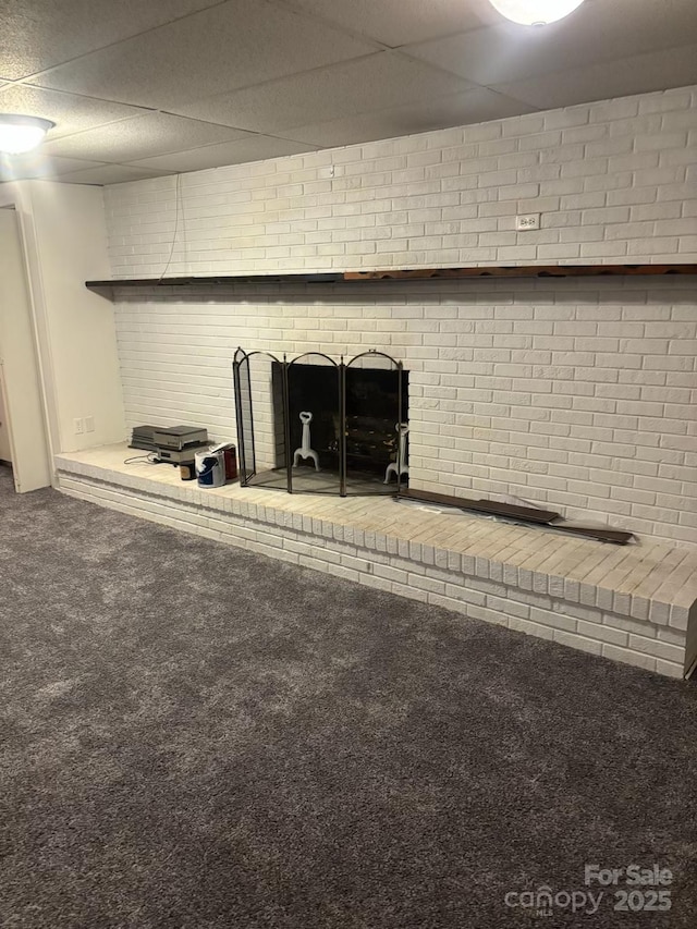 interior details with carpet, a paneled ceiling, and a brick fireplace