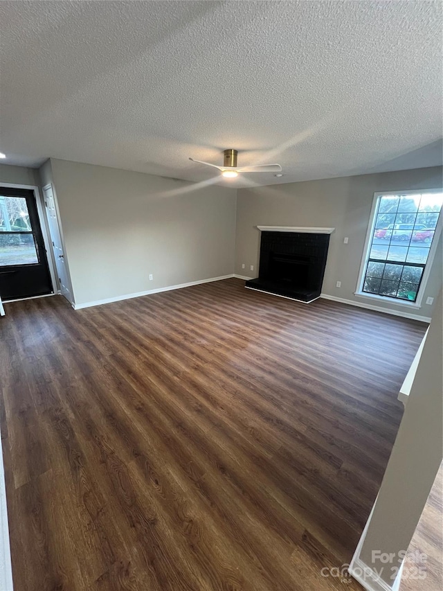 unfurnished living room with a textured ceiling, dark hardwood / wood-style flooring, and ceiling fan