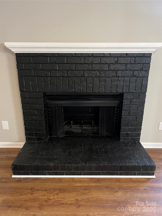 interior details featuring hardwood / wood-style flooring and a brick fireplace