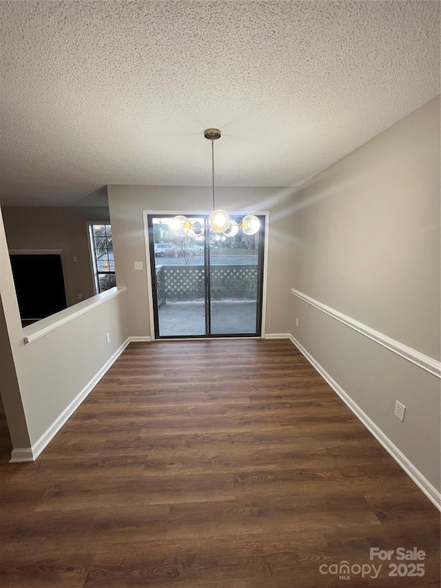 unfurnished dining area featuring a textured ceiling and dark hardwood / wood-style flooring