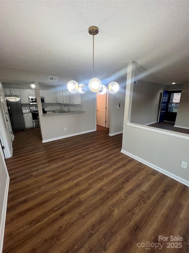 unfurnished dining area with a textured ceiling and dark wood-type flooring