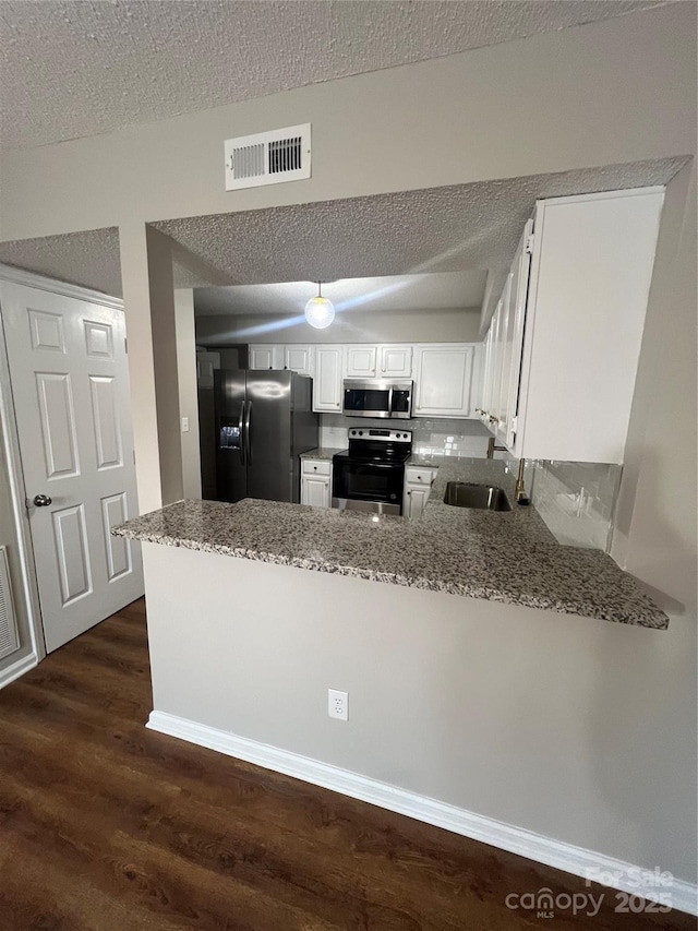 kitchen with kitchen peninsula, stainless steel appliances, and white cabinets