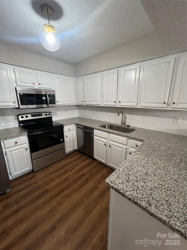 kitchen featuring appliances with stainless steel finishes, a textured ceiling, white cabinetry, and sink