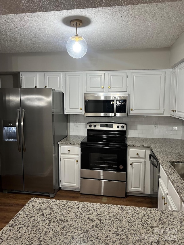 kitchen with white cabinets, appliances with stainless steel finishes, backsplash, and hanging light fixtures