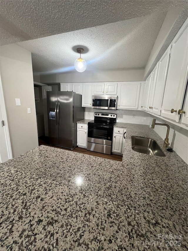 kitchen featuring white cabinetry, sink, dark stone counters, a textured ceiling, and appliances with stainless steel finishes