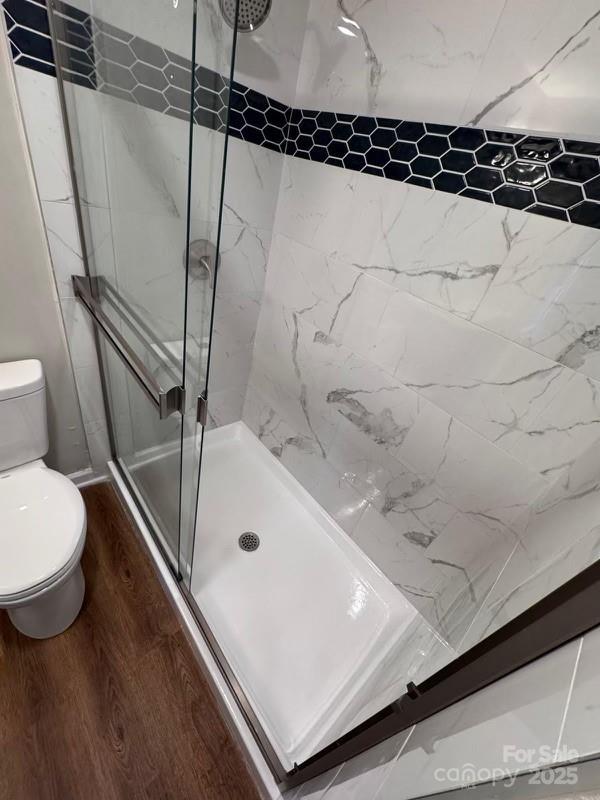 bathroom with walk in shower, wood-type flooring, and toilet