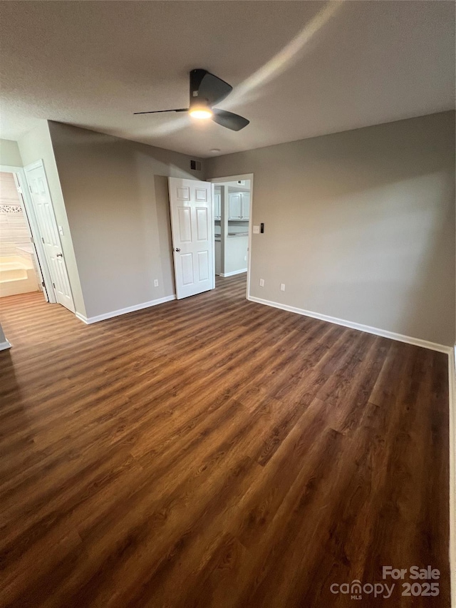 unfurnished bedroom featuring ensuite bathroom, ceiling fan, and dark wood-type flooring