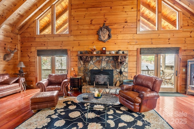 living room featuring a wood stove, beamed ceiling, high vaulted ceiling, hardwood / wood-style floors, and wood ceiling