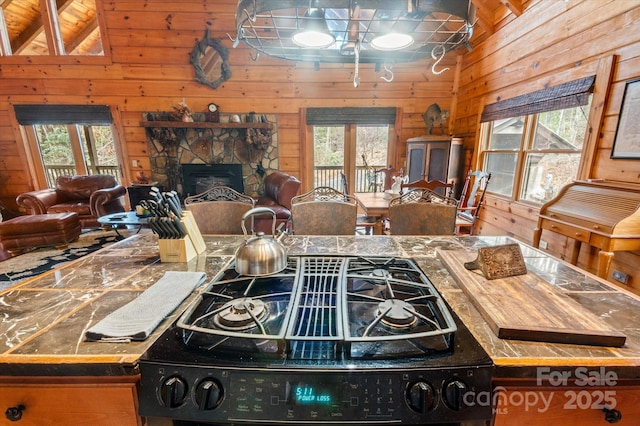 kitchen featuring wood walls, range, a fireplace, and a wealth of natural light