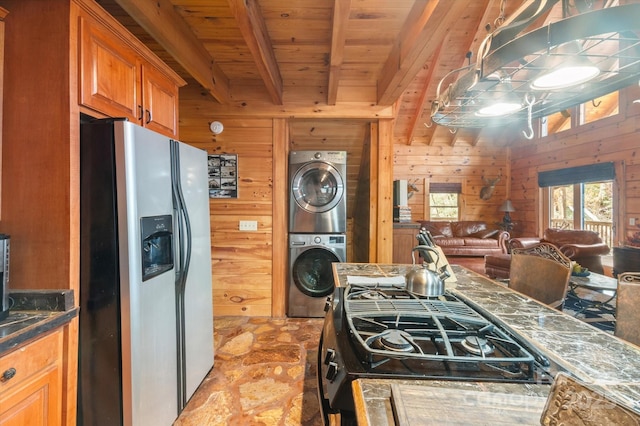 kitchen with stacked washing maching and dryer, beamed ceiling, stainless steel fridge, wooden walls, and wood ceiling