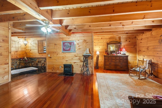 interior space with beamed ceiling, hardwood / wood-style flooring, and a wood stove