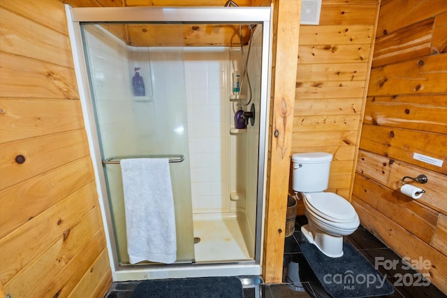 bathroom with wood walls, toilet, and walk in shower